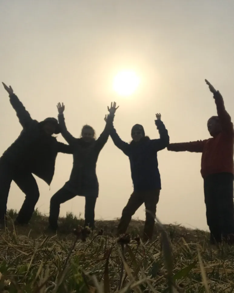 夕日の下で手を広げる人たち